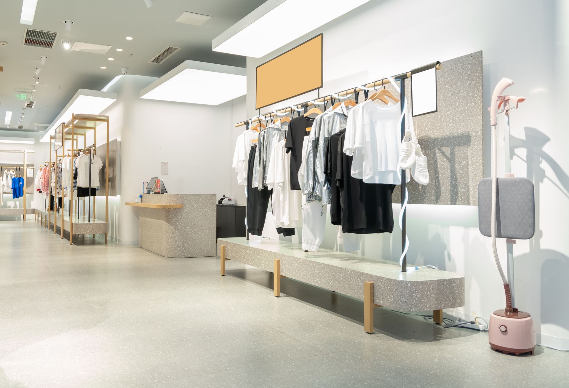 Intérieur d'un magasin de vêtements avec des portants et un défroisseur vapeur.