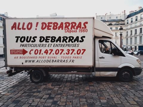 Camion blanc arborant le logo Allo! Débarras dans une rue pavée de Paris.