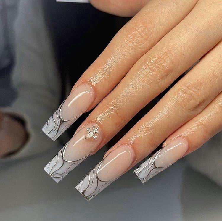 Un primer plano de las uñas de una mujer con manicura francesa.