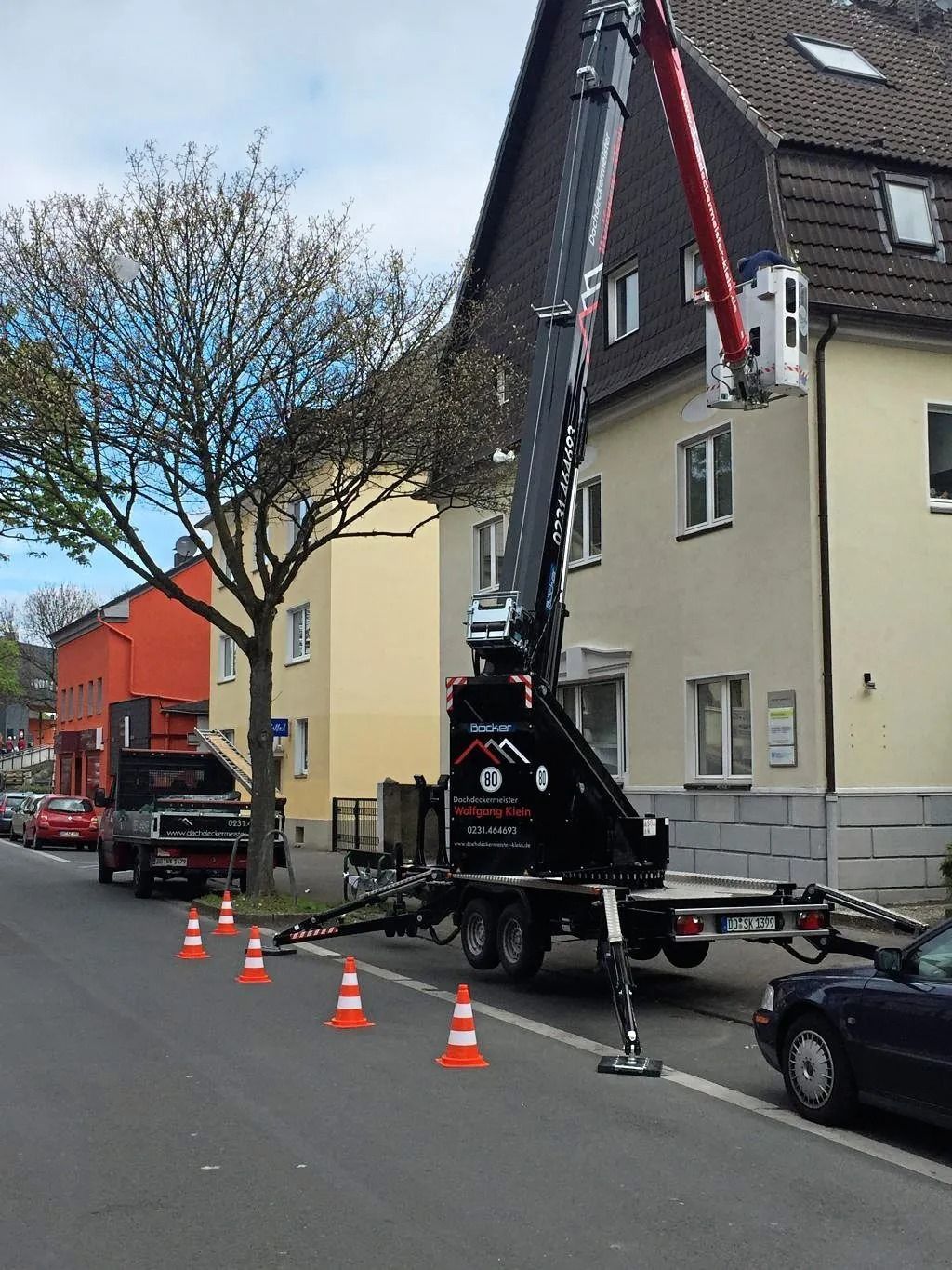 Ein schwarzer Mobilkran, der auf einer mit Verkehrskegeln abgesperrten Straße in der Stadt parkt,