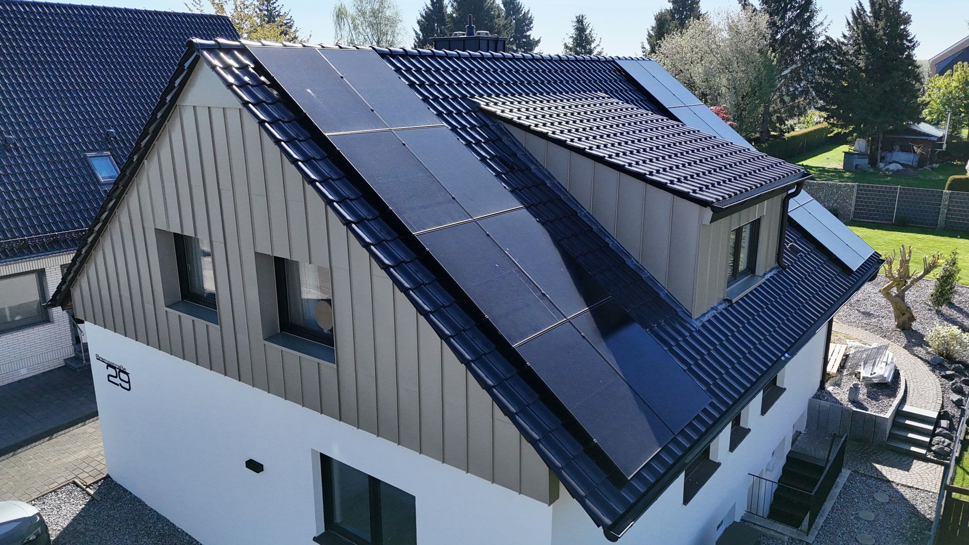 Modernes Hausdach mit dunklen Solarpaneelen und Oberlichtern unter hellem Himmel