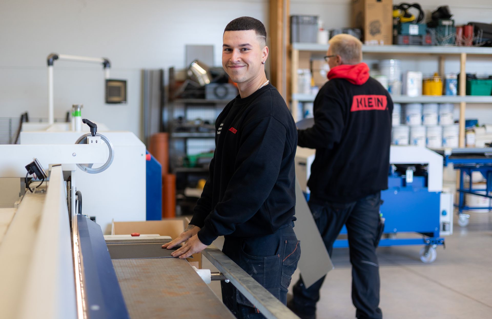 Zwei Arbeiter von der Klein GmbH in einer Werkstatt neben einer großen Industriemaschine