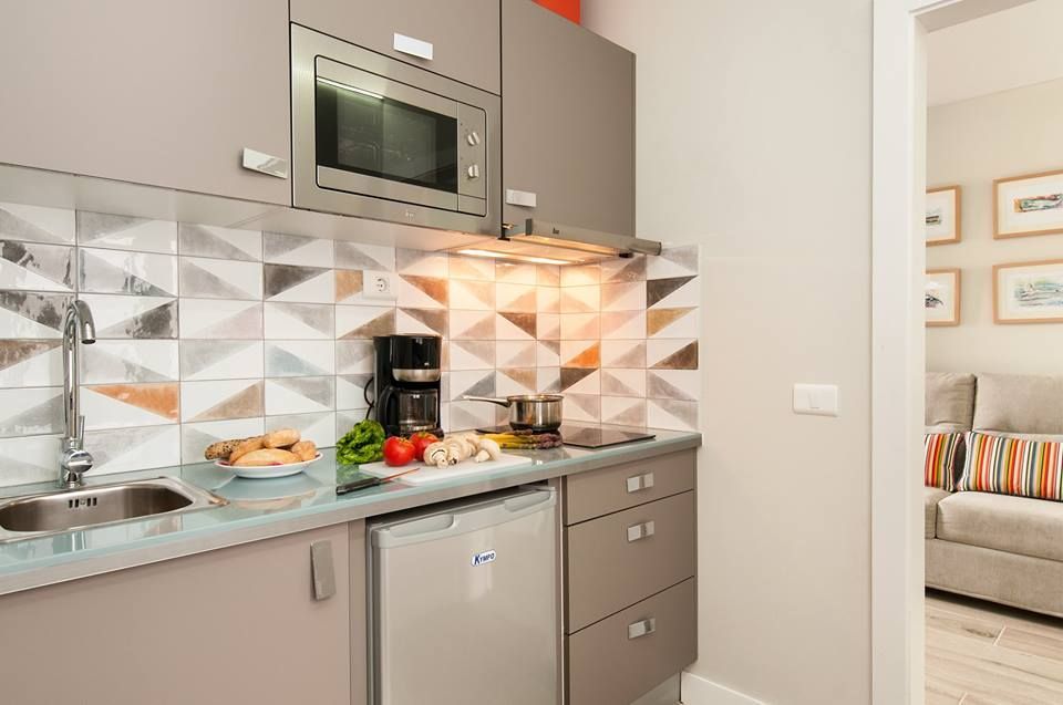 Una cocina con fregadero, estufa, microondas y lavavajillas.