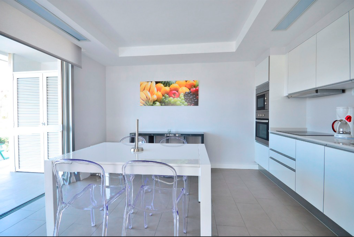 Una cocina con una mesa y sillas y un cuadro de fruta en la pared.