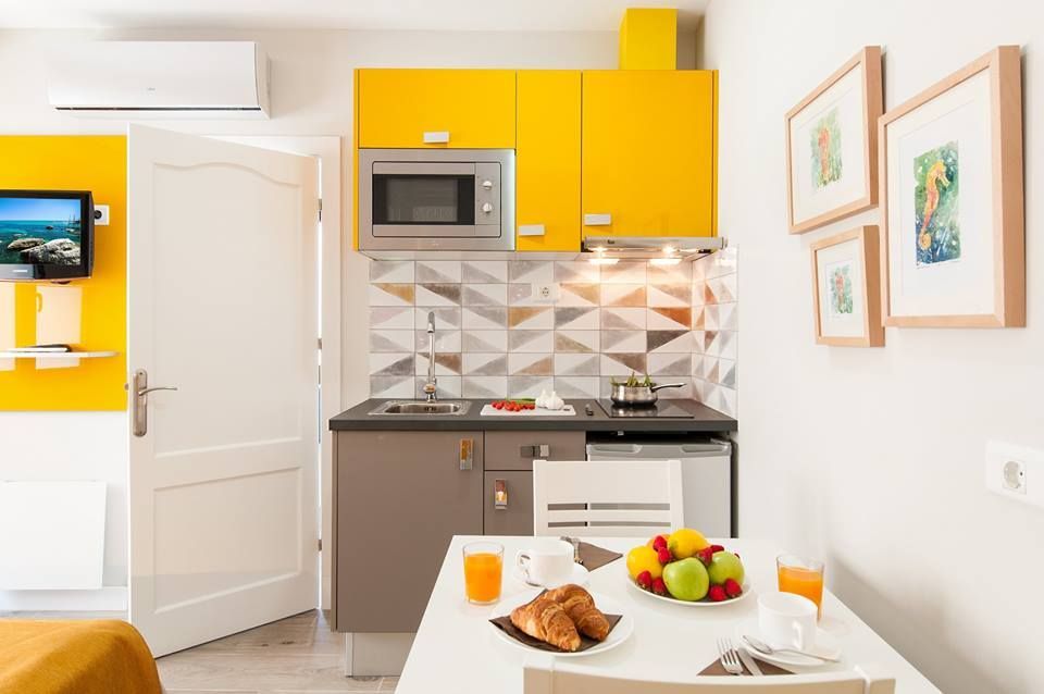 Una cocina con gabinetes amarillos y una mesa con fruta encima.