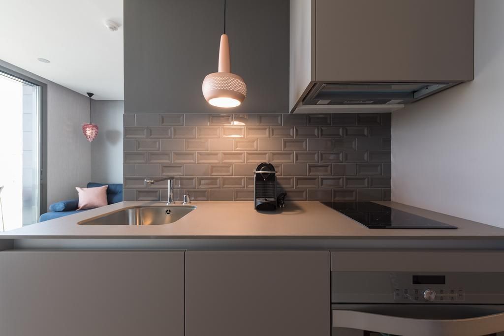 Una cocina con fregadero, estufa, lavavajillas y una pared de ladrillo.