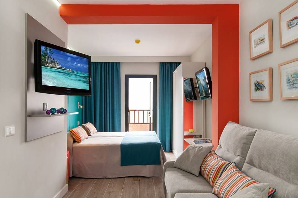 Una habitación de hotel con cama, sofá, televisión y balcón.