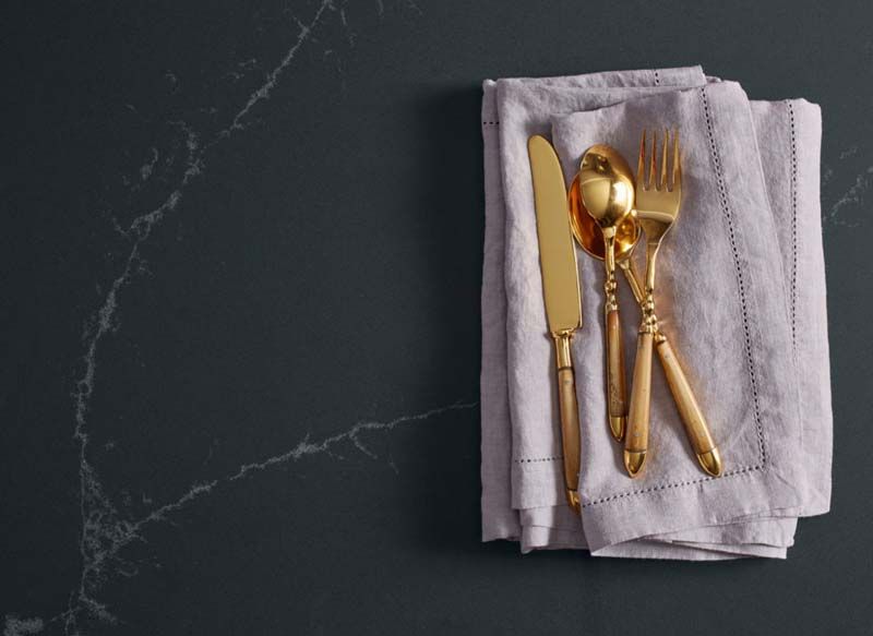 La cubertería de oro reposa sobre una servilleta sobre una mesa.