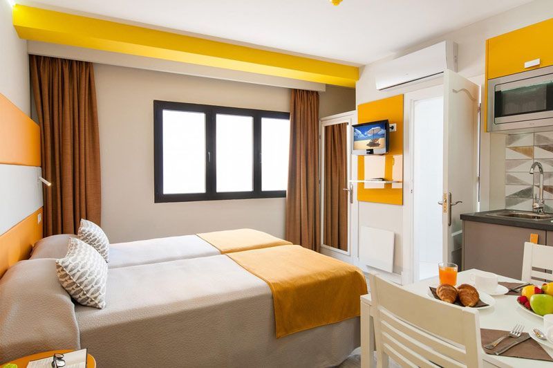 Una habitación de hotel con dos camas, una mesa y una televisión.