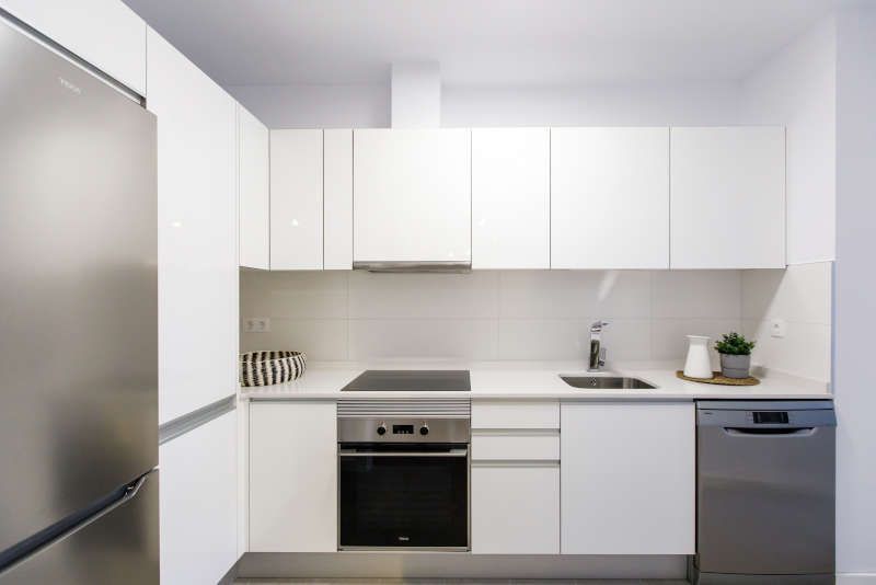 Una cocina con gabinetes blancos y electrodomésticos de acero inoxidable.