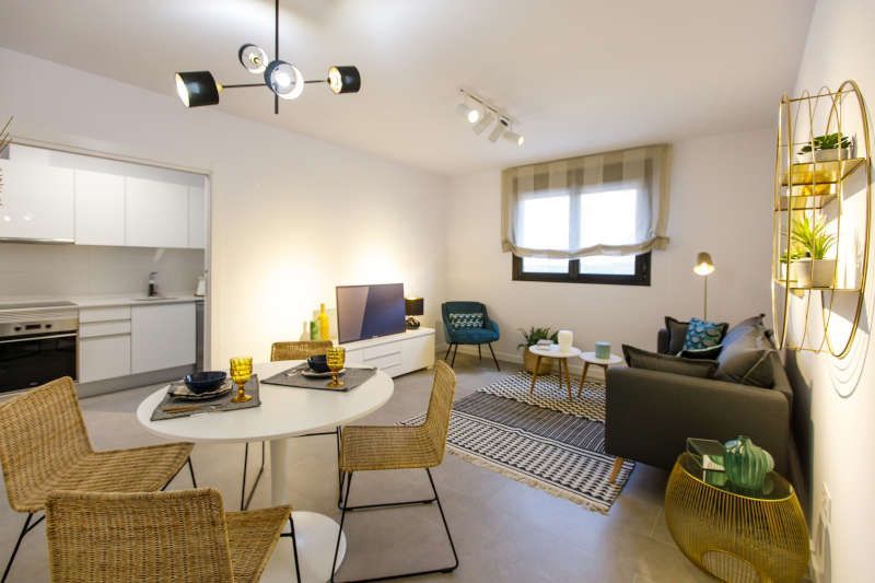 Una sala de estar con sofá, mesa, sillas y una cocina.