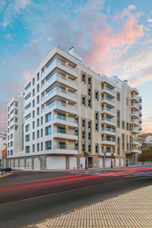 Un gran edificio con muchos balcones está situado al costado de una calle.