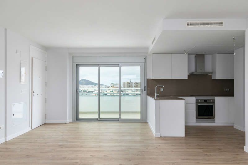 Un apartamento vacío con cocina y puertas corredizas de vidrio.