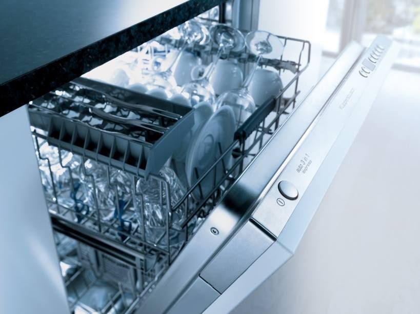 Un lavavajillas con una cesta llena de vasos y tazas.