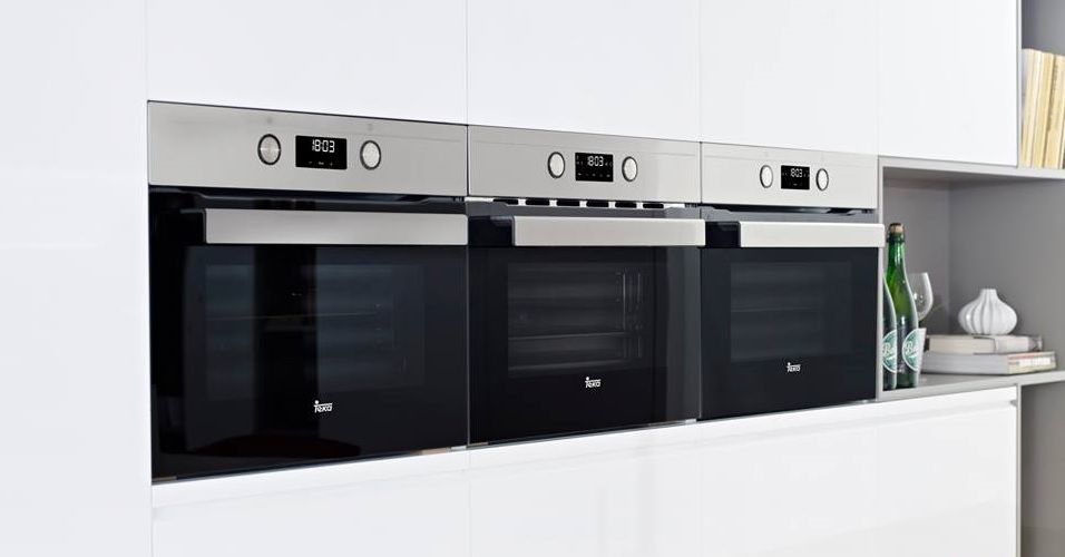 Tres hornos de acero inoxidable están alineados en una cocina.