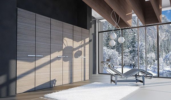 Una sala de estar con un sofá y una gran ventana con vista a un bosque nevado.