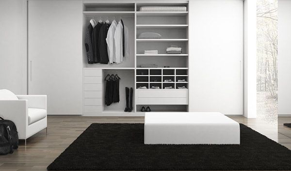 Una sala de estar con una silla, una otomana, una alfombra y un armario.