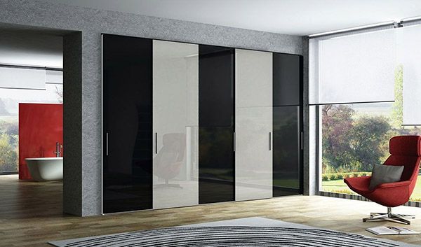 Una sala de estar con un armario blanco y negro y una silla roja.