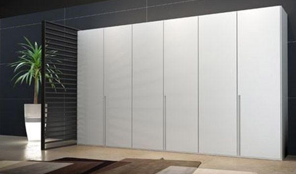 Un gran armario blanco está en una habitación al lado de una planta.