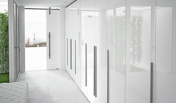 Un pasillo largo con armarios blancos y una puerta.