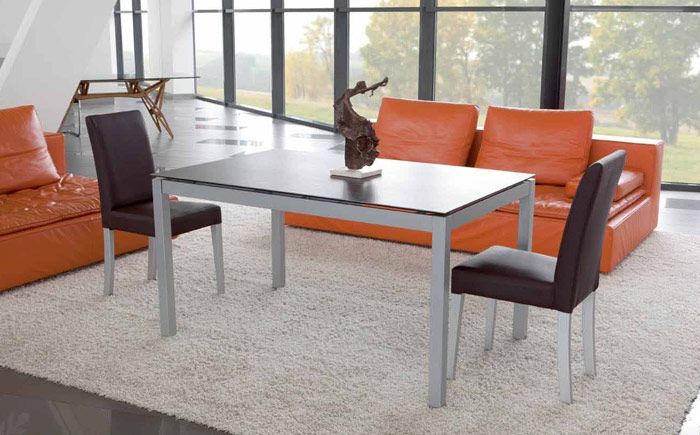 Una sala de estar con una mesa y sillas y un sofá naranja.