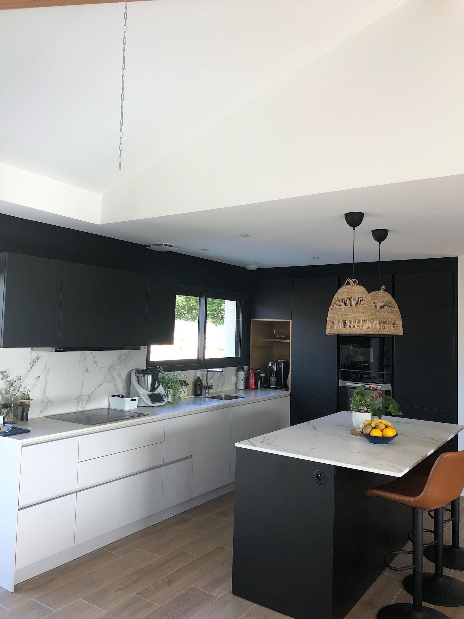 Cuisine noire et blanche avec luminaire au-dessus de l'îlot central