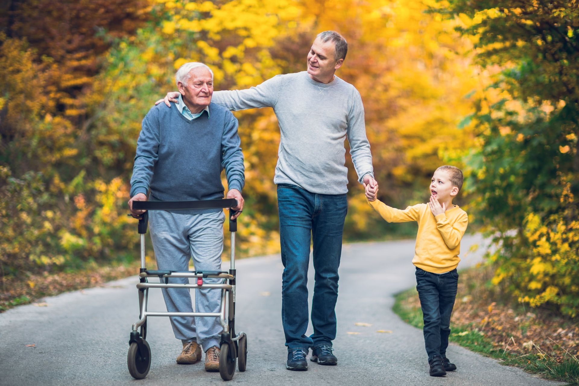 Une famille en balade dont le grand-père avec un déambulateur.