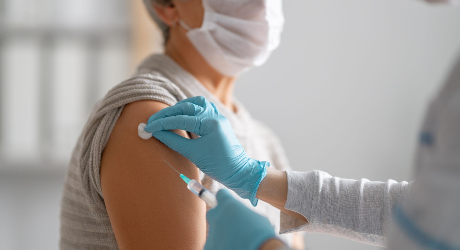 Une dame se fait vacciner par un professionnel de santé.