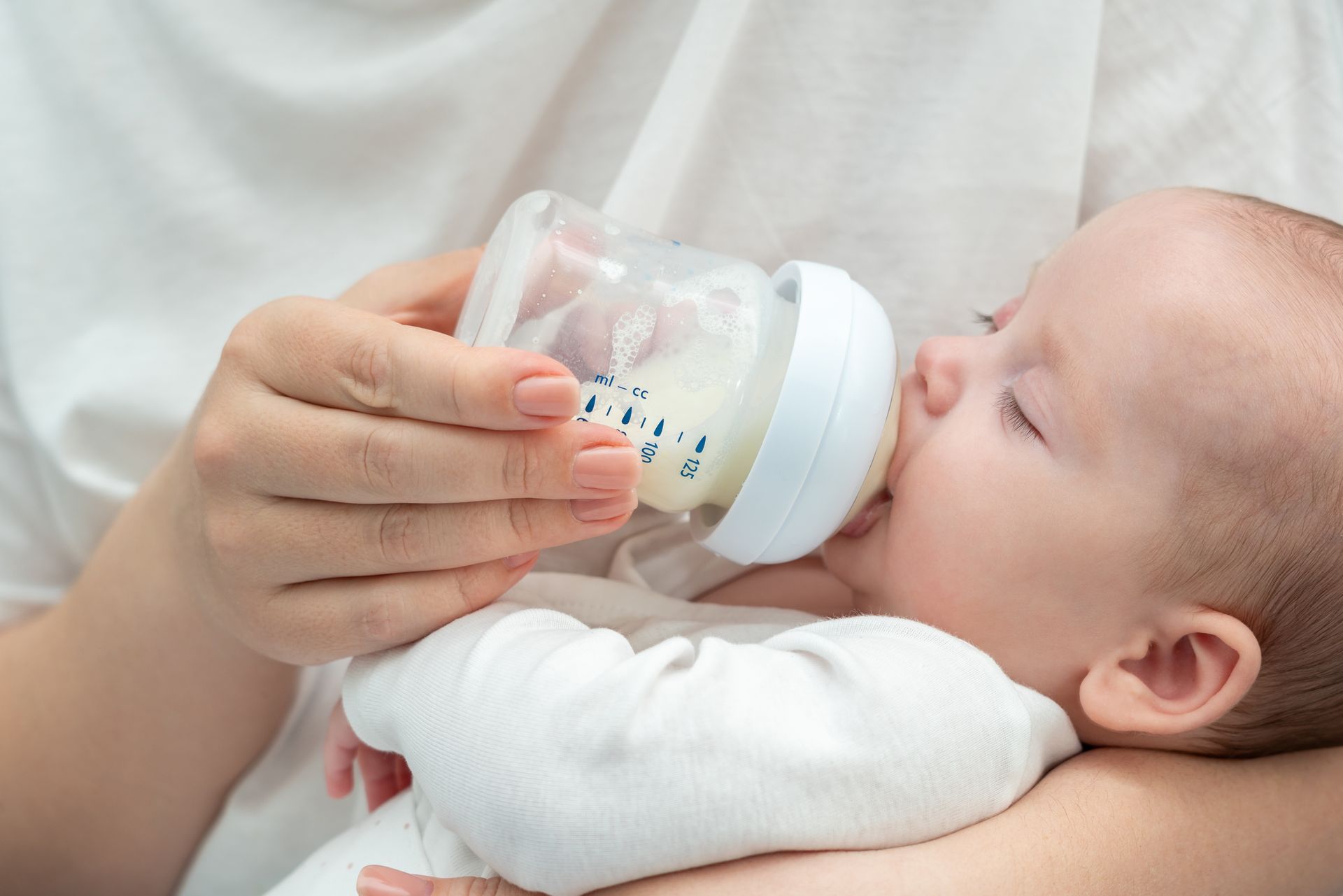 Un bébé boit du lait au bibéron.