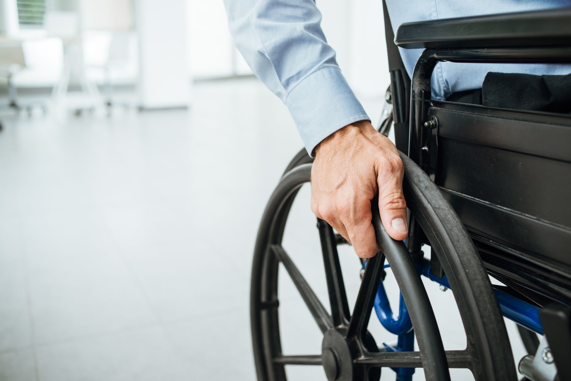 Une main sur la roue d'un fauteuil roulant.