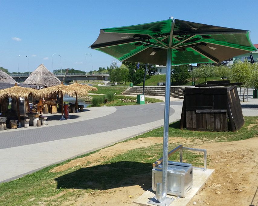 Un parasol vert et noir composé de panneaux solaires au-dessus est posé sur l'herbe