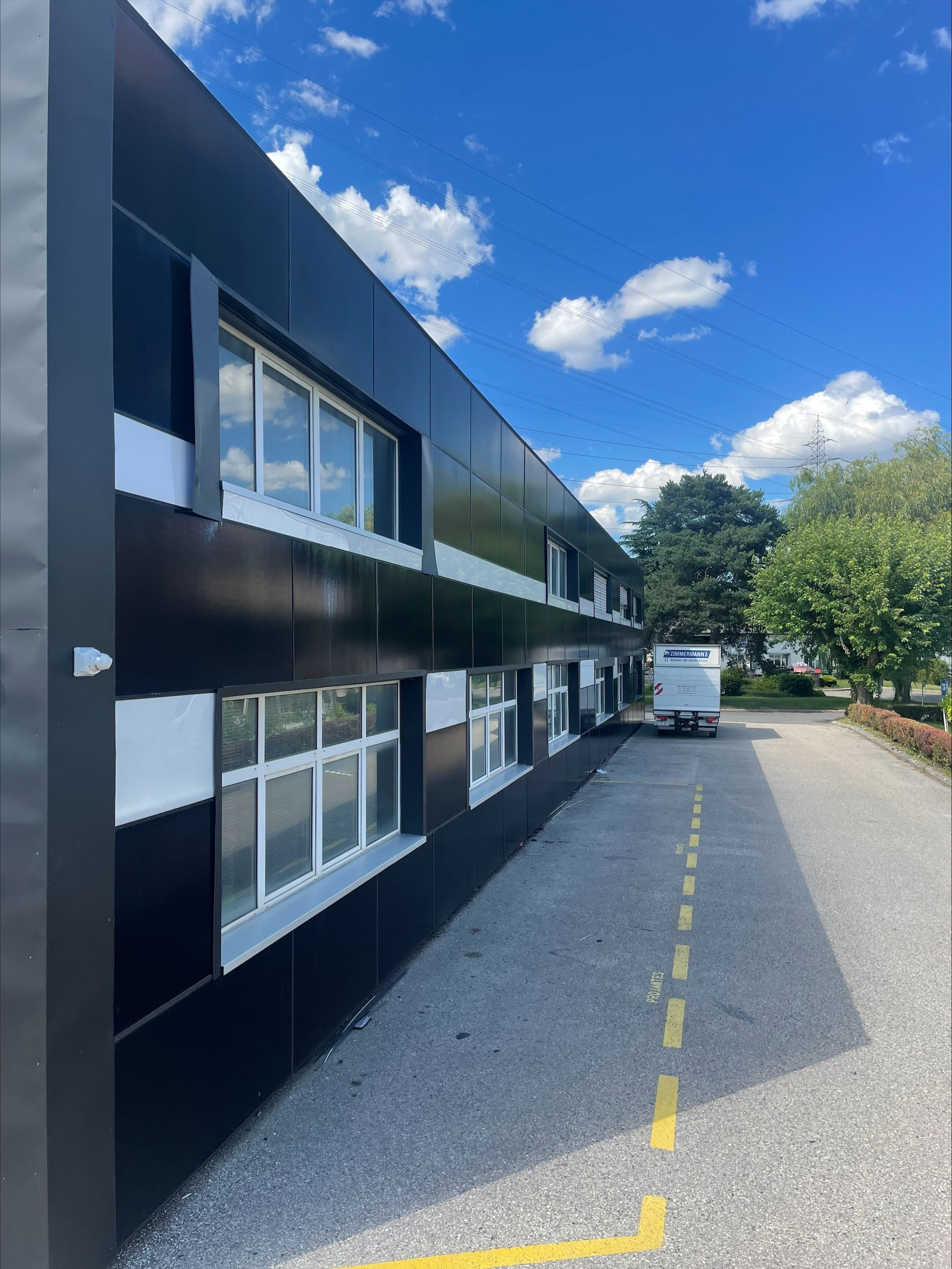 Un bâtiment noir et blanc avec des panneaux solaires sur la façade