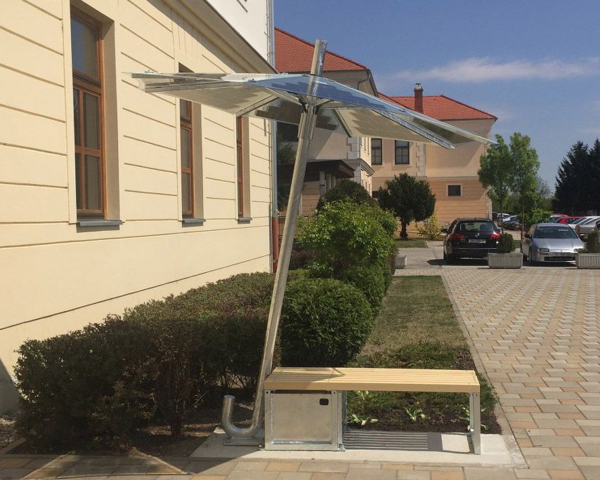 Un banc devant un bâtiment avec un auvent composé de panneaux solaires au-dessus
