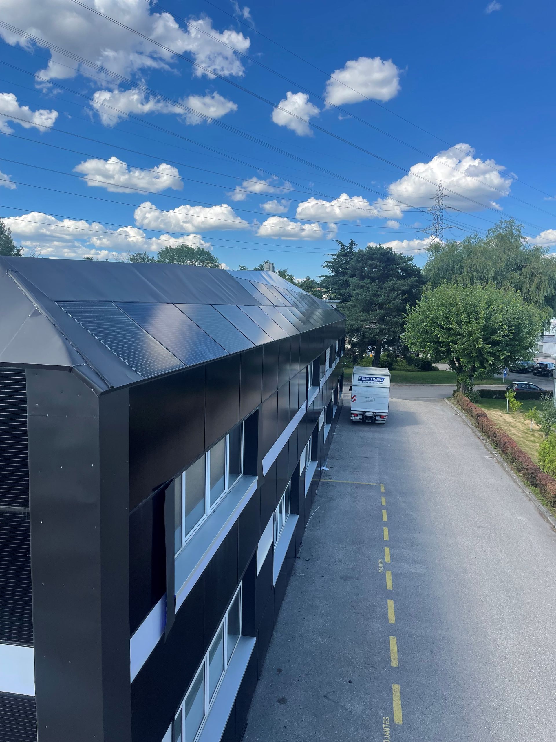Un bâtiment noir et blanc avec des panneaux solaires sur le toit