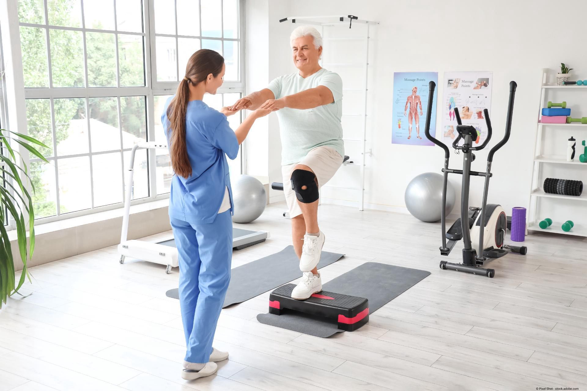 Pflegerin hilft älterem Mann bei Physiotherapie