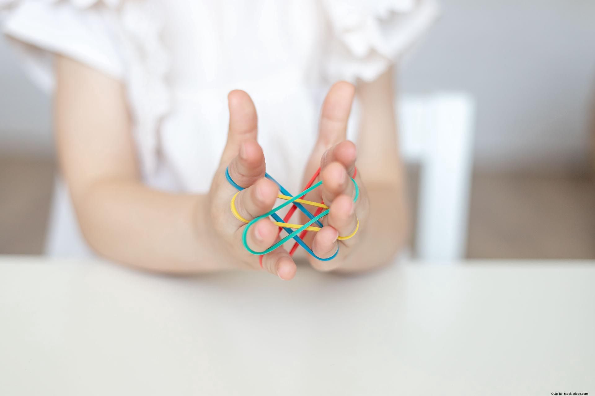 Übungen mit der Hand: Frau nutzt Gummibänder um die Koordination der Finger zu stärken.