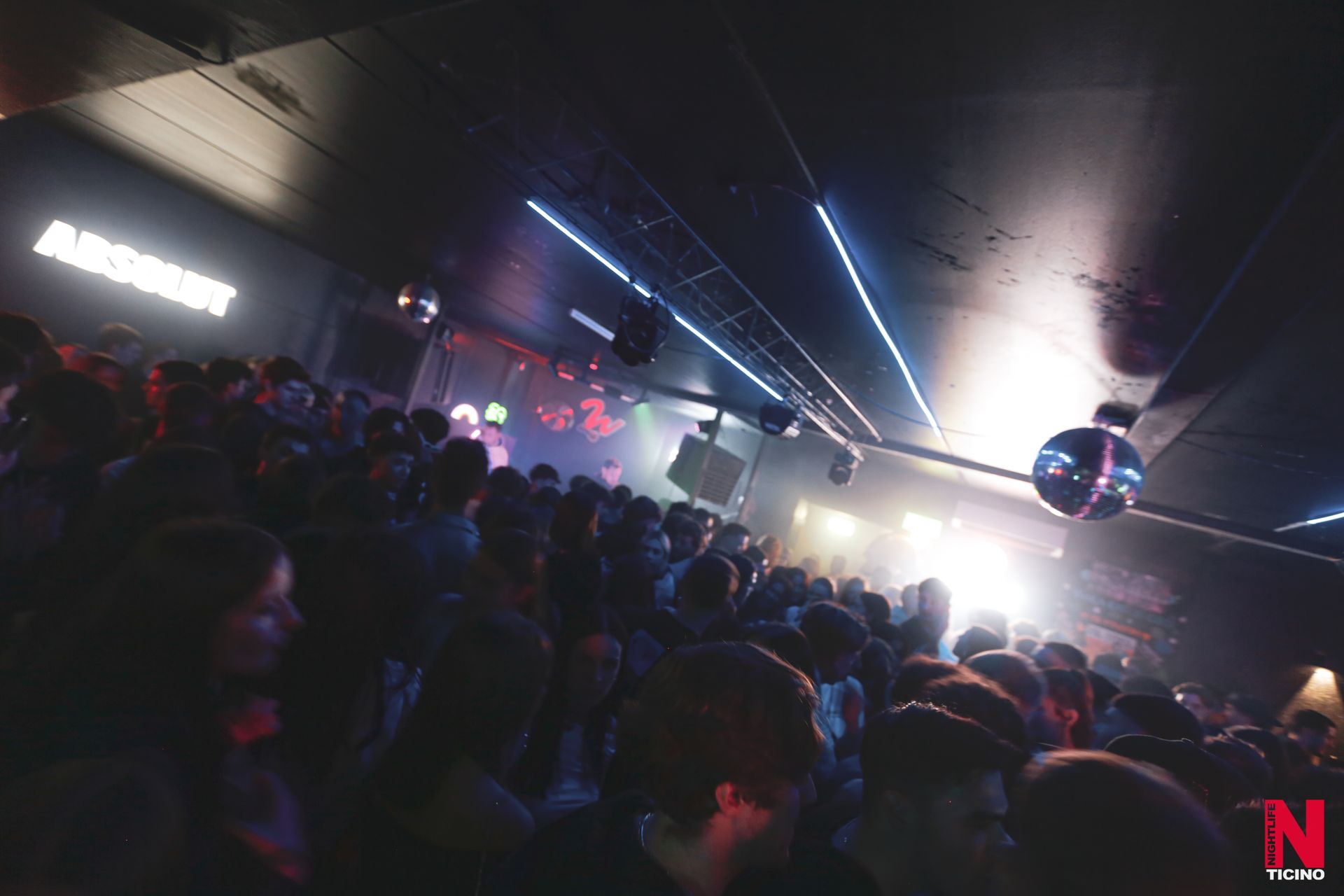 Diverse sfere da discoteca argentate poggiano su una superficie bianca davanti a scintillanti tende di frange argentate.