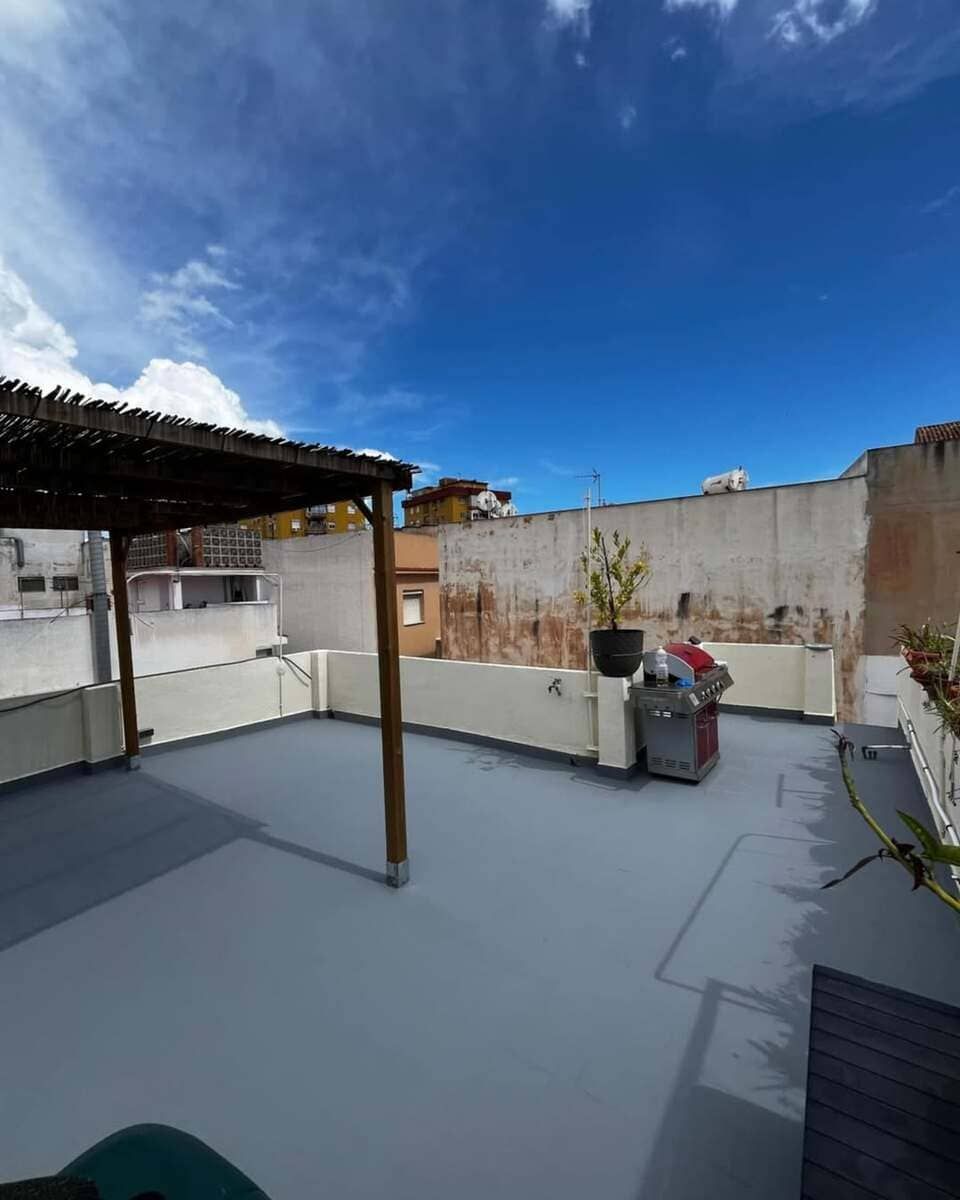 Una azotea con una pérgola y un cielo azul al fondo