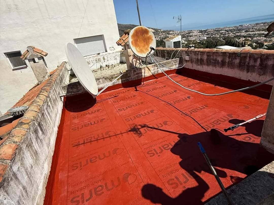Un patio con una mesa y sillas frente a un edificio blanco.