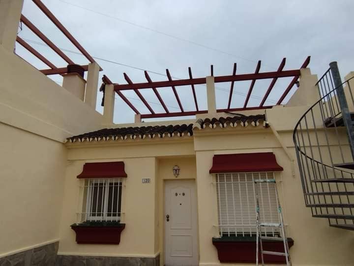 Una casa blanca con un toldo rojo y una escalera de caracol