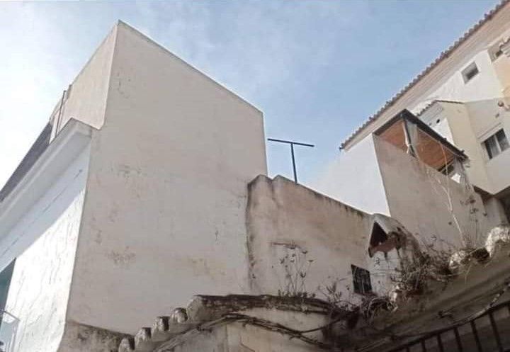 Un edificio blanco con una antena parabólica encima.