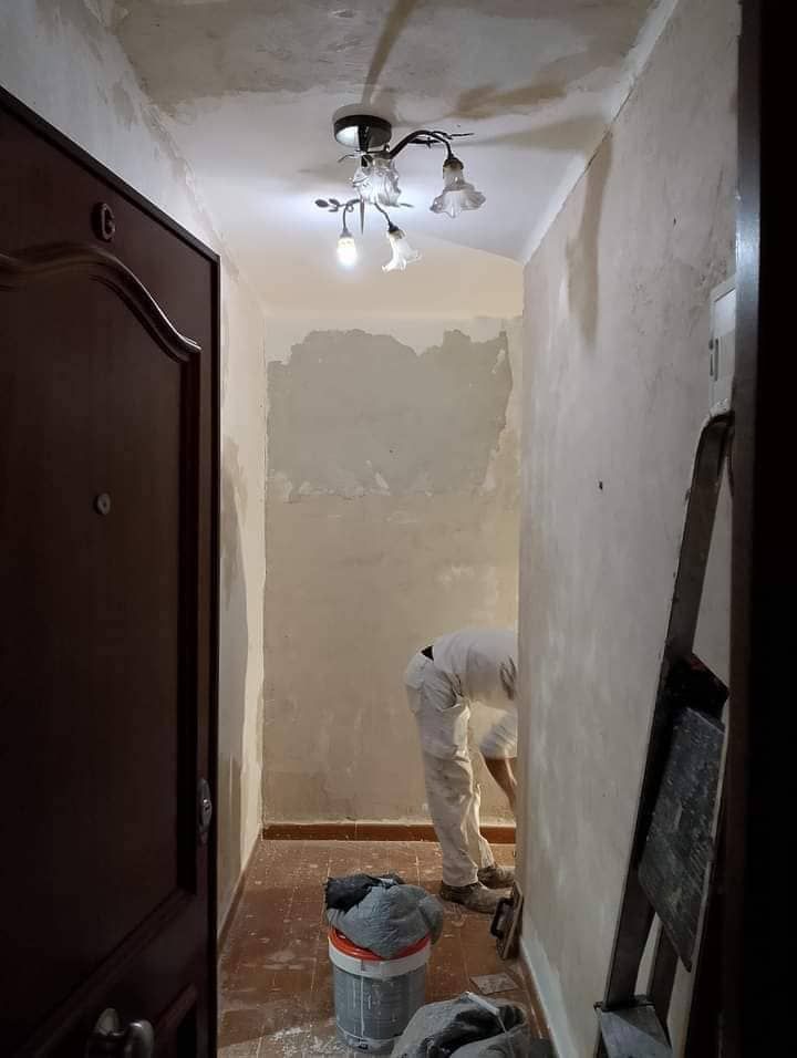 Un hombre está pintando una pared en un pasillo.