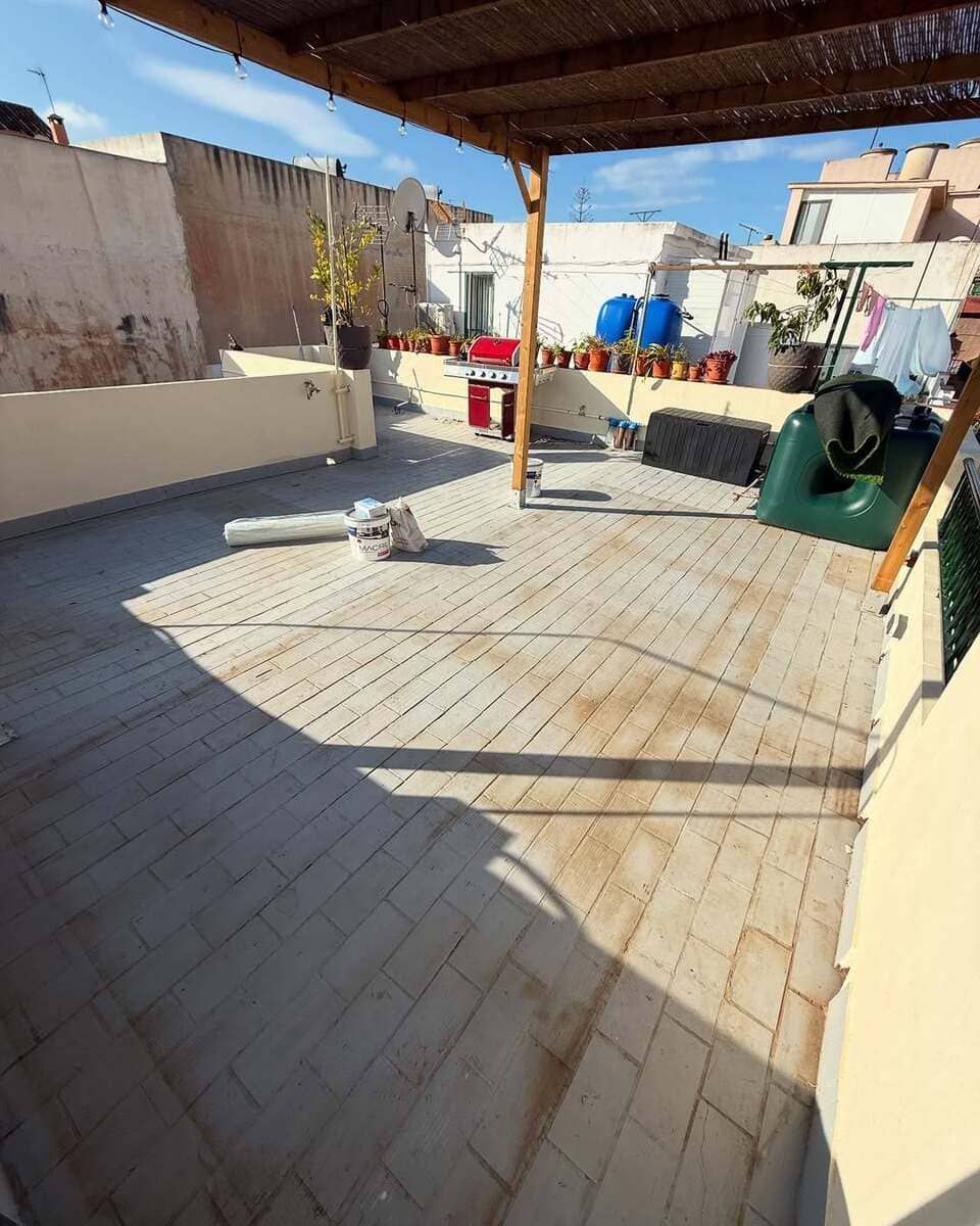 Una azotea con una pérgola de madera y muchas plantas en macetas.