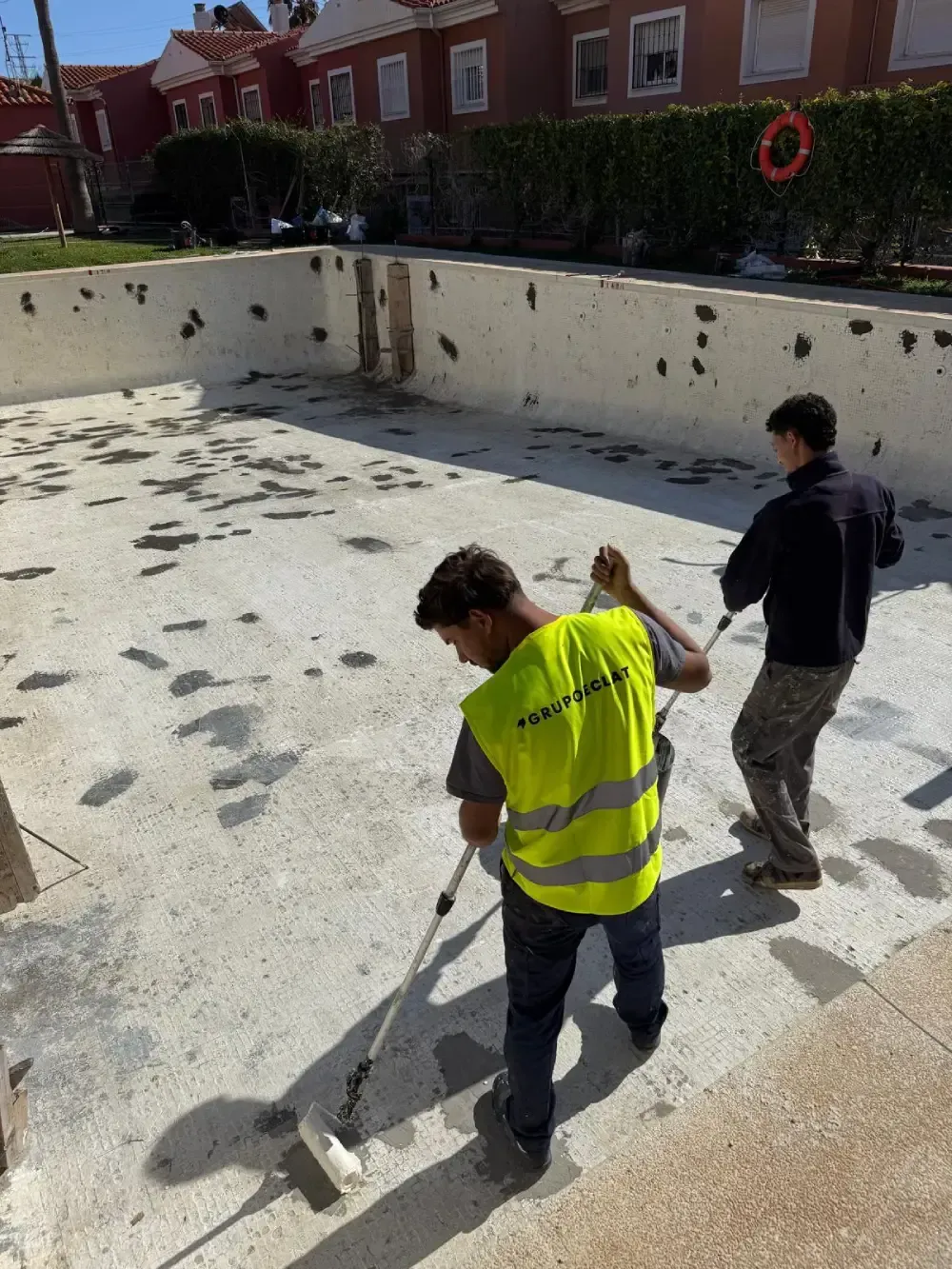 Un patio con una mesa y sillas frente a un edificio blanco.