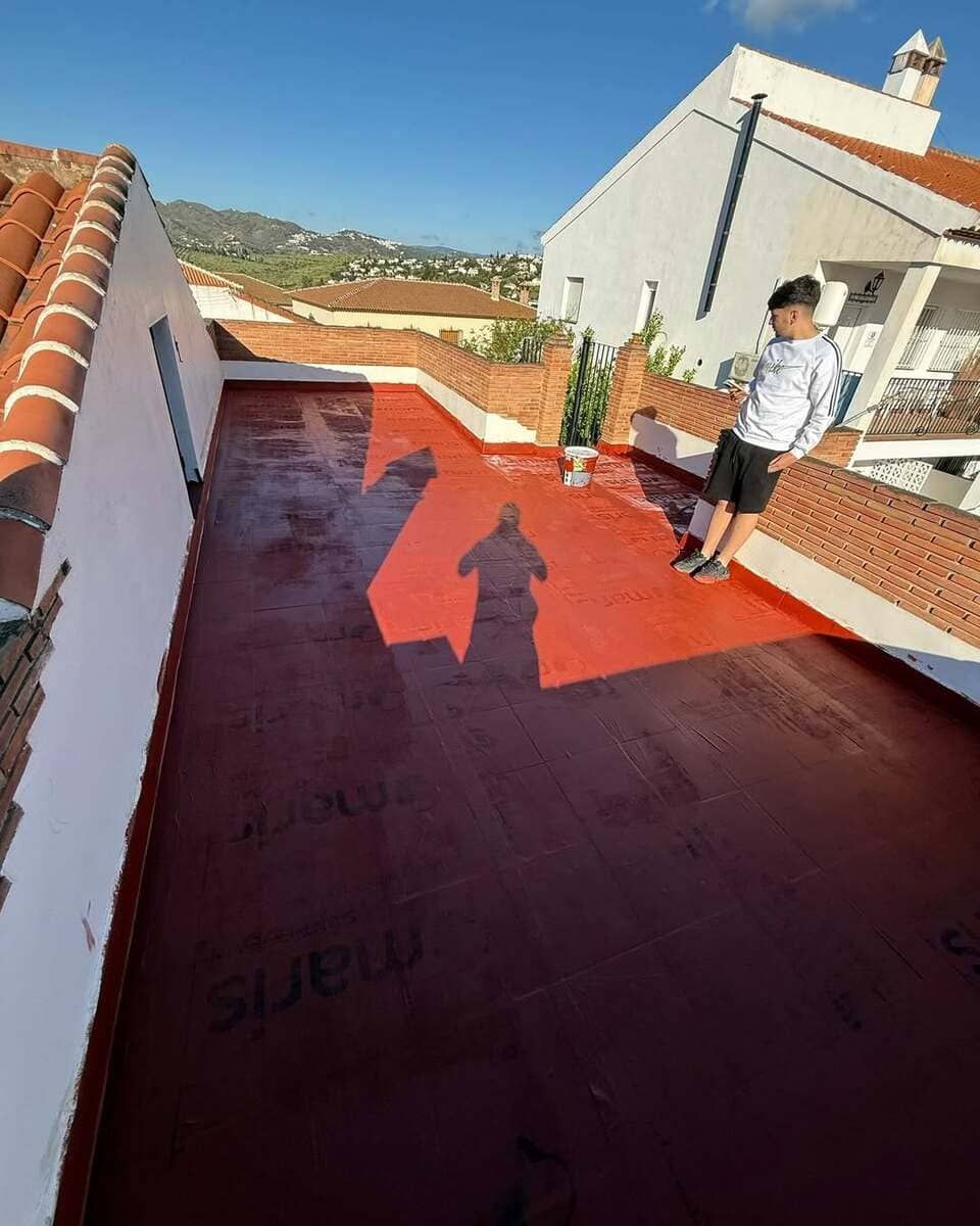 Dos hombres están trabajando en un tejado con una antorcha.