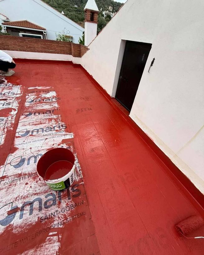 Un hombre está pintando el costado de una casa blanca.