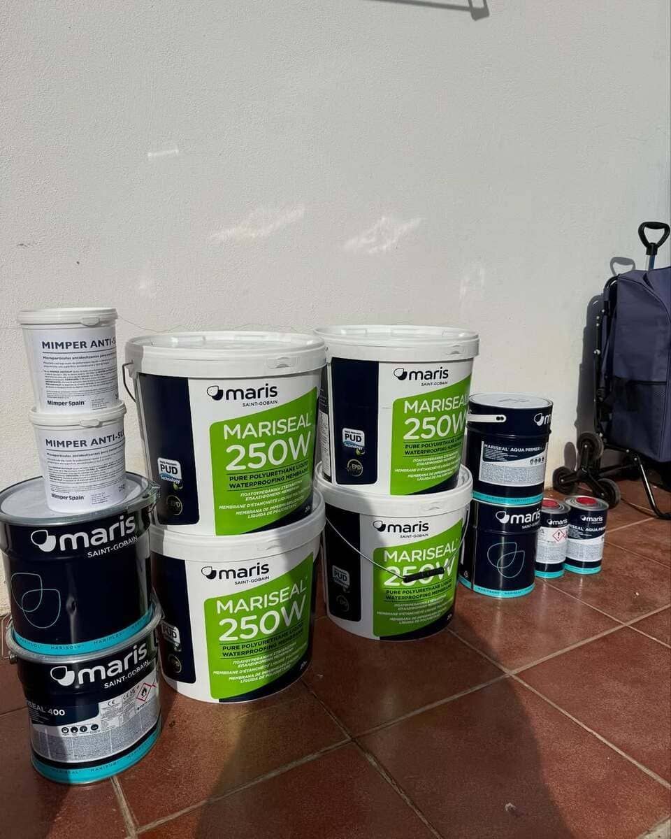 Un montón de cubos de pintura están apilados uno encima del otro sobre un piso de baldosas.