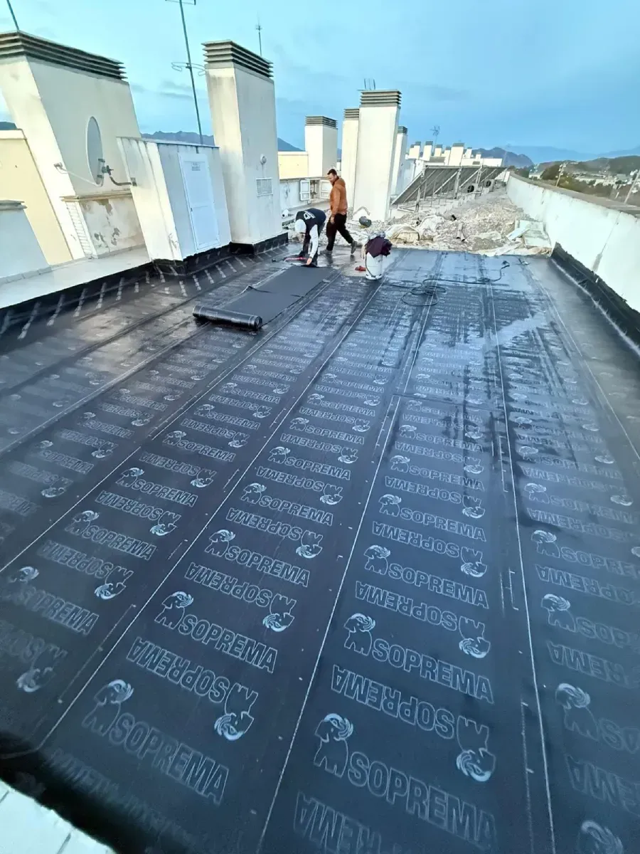 Dos hombres están trabajando en un tejado con una antorcha.