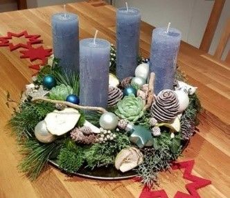 Ein Weihnachtskranz mit blauen Kerzen und Dekorationen auf einem Holztisch.
