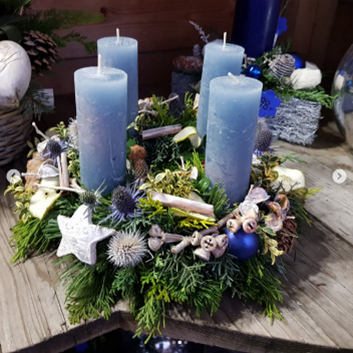 Ein Weihnachtskranz mit blauen Kerzen und Grün auf einem Holztisch